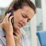 Woman holding her cell phone with one hand and her neck with the other in pain after she was in a car accident thinking about hiring an attorney